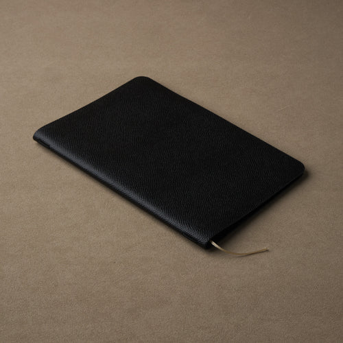The Pensift leather cover closed at a three-quarter angle, showing the Epsom grain and beige ribbon.