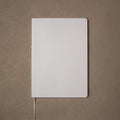 Pensift Notebook from above: a plain Paper Grey cover with rounded corners, on a camel background