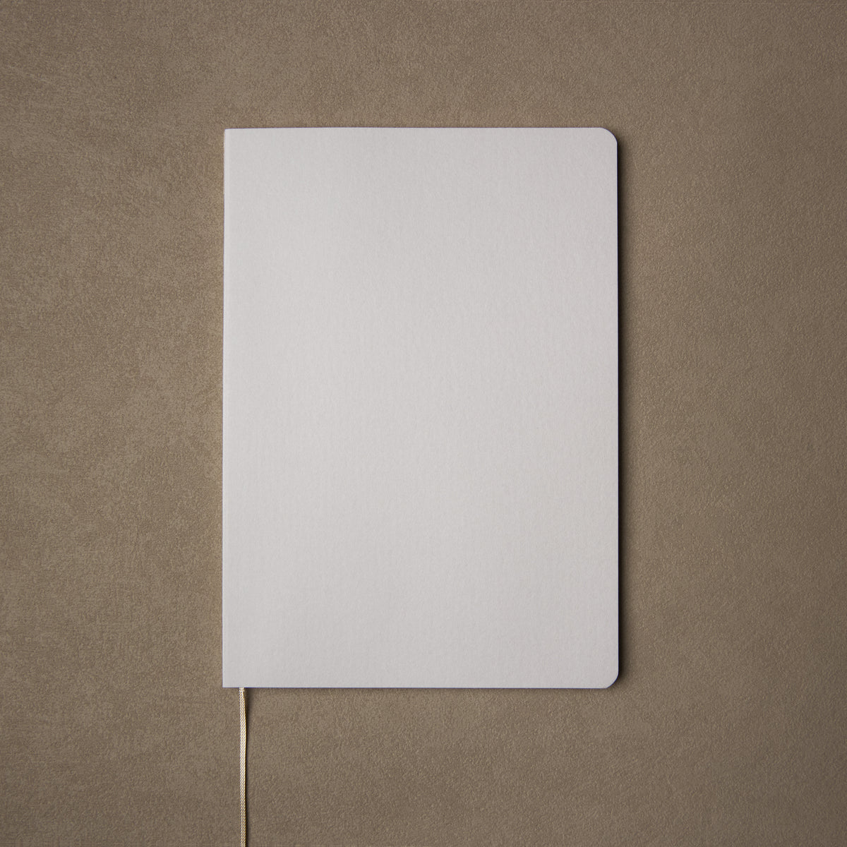 Pensift Notebook from above: a plain Paper Grey cover with rounded corners, on a camel background