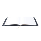 An open Pensift Notebook demonstrating its completely lay-flat design, revealing the dot grid pages and bookmark ribbon.